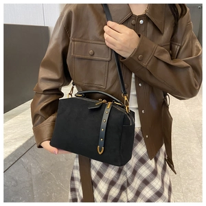 Détail du sac polochon en daim noir avec clous dorés et finitions métalliques chics