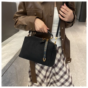 Détail du sac polochon en daim noir montrant la texture mate et les clous dorés