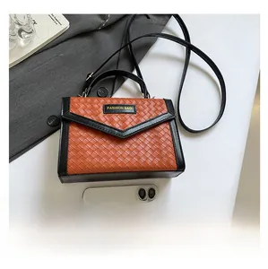 Top-down view of woven leather handbag in orange and black with adjustable shoulder strap