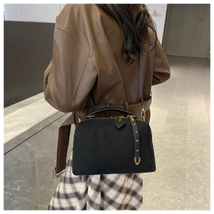 Détail du sac Boston en daim noir avec boucles dorées mates et bandoulière brodée