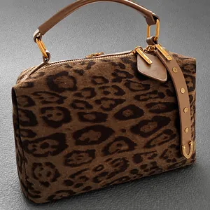 Détail du sac boston en daim léopard avec poignées en cuir et boucles métalliques en laiton