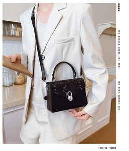 Detail view of retro snake print flap handbag with silver metal lock on white blazer