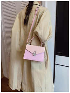 Detail of pink faux leather crossbody bag with snake print flap and silver clasp