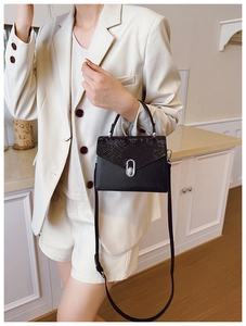Detail of black faux leather crossbody bag with snake skin pattern and silver buckle