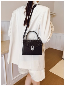 Detail shot of black faux leather crossbody bag featuring snakeskin textured flap and silver lock