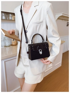 Detail of elegant snake-print box bag with silver metal lock on a stylish white suit