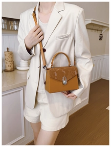 Detail of caramel crossbody bag with faux snakeskin flap and silver oval buckle