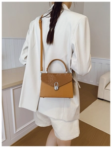 Model wearing a yellow snakeskin pattern box bag with a silver twist lock clasp