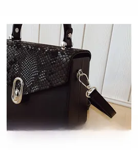 Detail of silver hardware hooks and snake-patterned texture on a black luxury box bag