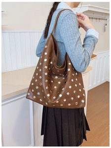Détail des rivets argentés sur un grand sac cabas en cuir marron foncé au style rétro