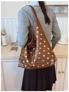 Détail du sac hobo en cuir marron souple avec des rivets décoratifs en métal argenté
