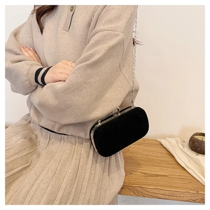 Détail de pochette de soirée en velours noir avec chaîne argentée et fermoir strass