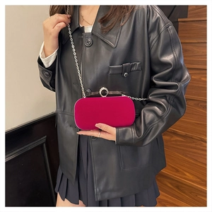 Détail de la pochette en velours fuchsia avec boucle en cristal et chaîne sur un mannequin