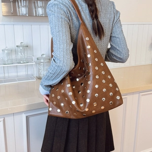 Sac Hobo marron foncé avec clous argentés en similicuir brillant porté par mannequin