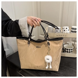 Détail du cabas plissé kaki avec poignées sombres et breloque en peluche décorative