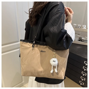 Vue détaillée du grand sac cabas kaki plissé avec pendentif en peluche porté à l'épaule