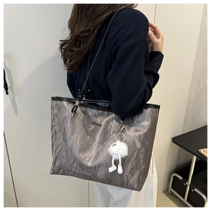 Detail of silver metallic wrinkled tote bag featuring a cute white plush pendant