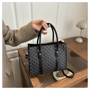 Close-up of a vintage monogram tote bag with leather handles and gold-tone hardware