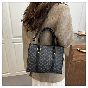 Detailed view of the monogram letter print and black handles on large tote bag