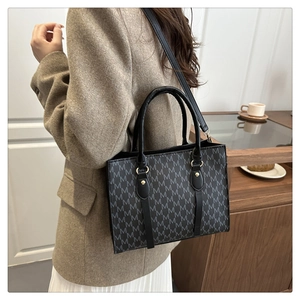 Classic M-pattern tote bag shown in a lifestyle setting with top handle and crossbody strap
