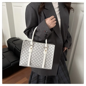 Close-up of retro M-pattern tote bag showing white handle and gold hardware details