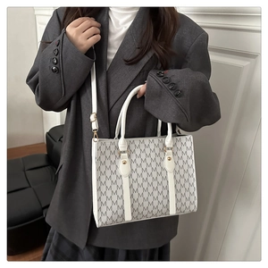 Detail of white tote bag with grey M-letter pattern and adjustable shoulder strap