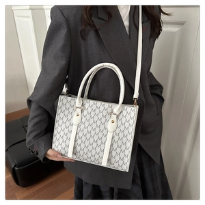 Detailed close-up of a white tote bag with grey letter prints and leather handles
