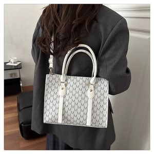 Close-up of white and grey patterned handbag with M letter prints and gold hardware