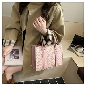 Detail of pink monogram tote bag with M-pattern and sturdy handles in office setting