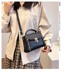 Close-up of black litchi pattern leather bag with silver metal swivel lock and side zippers