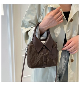 Macro detail of dark brown bucket bag with unique shirt collar design and leather tag