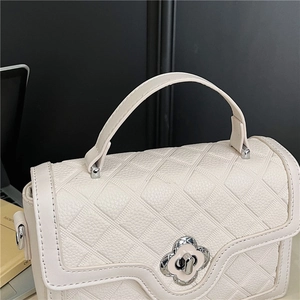 Detail of quilted leather handbag with silver clover lock and wave-edge flap