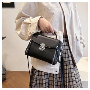 Close-up of black litchi pattern leather bag with silver metal swivel lock and side zippers