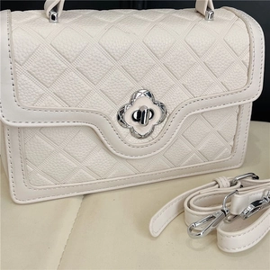 Detail of lychee pattern leather handbag featuring silver floral metal twist lock