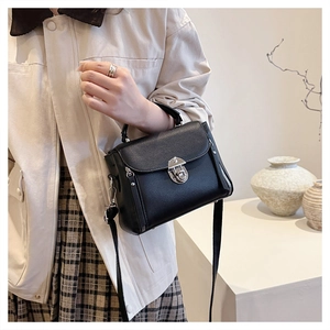 Close-up of black leather crossbody bag with silver rotating lock and lychee texture
