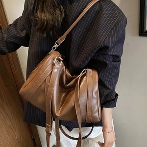 Sac fourre-tout en cuir marron avec texture plissée et bandoulière réglable sur modèle
