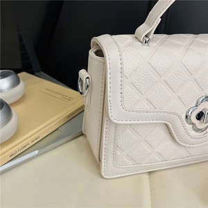 Detailed shot of cream quilted leather crossbody bag with a metal flower twist lock