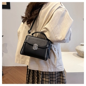 Detailed view of black textured leather crossbody bag with silver twist lock and strap