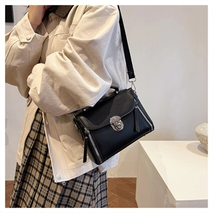 Detail of black crossbody bag featuring silver buckle and stylish side zipper accents