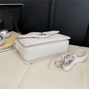 Detail of cream quilted crossbody bag featuring silver twist lock and detachable strap