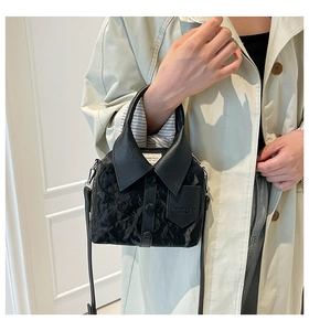 Close-up of shirt-style bucket bag featuring collar and button details on black leather