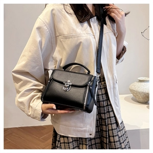 Model showing a black pebble leather crossbody bag with silver hardware on a simple background