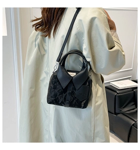Detail of creative shirt-collar design on a black glossy textured crossbody handbag