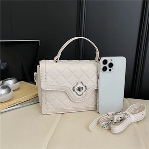 Close-up of quilted leather handbag with silver floral twist lock and phone for scale
