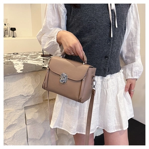 Detail of taupe crossbody bag with silver twist lock and premium litchi grain texture