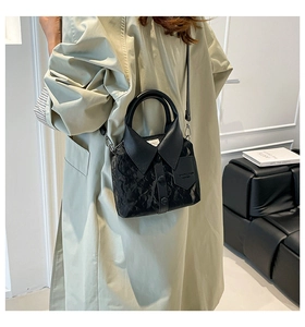 Detail of creative black shirt-shaped handbag with pleated texture and silver chain strap