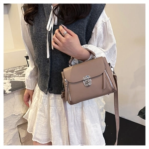 Detail of tan lychee-patterned bag with silver buckle and decorative side zippers