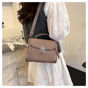 Detail of taupe pebbled leather bag with silver lock and adjustable shoulder strap