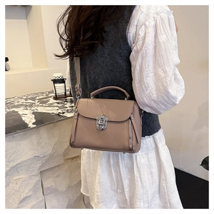 Close-up of taupe textured leather crossbody bag with silver twist-lock and side zippers