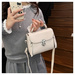 Detail of a beige PU leather crossbody bag with silver rotating clasp and side zipper